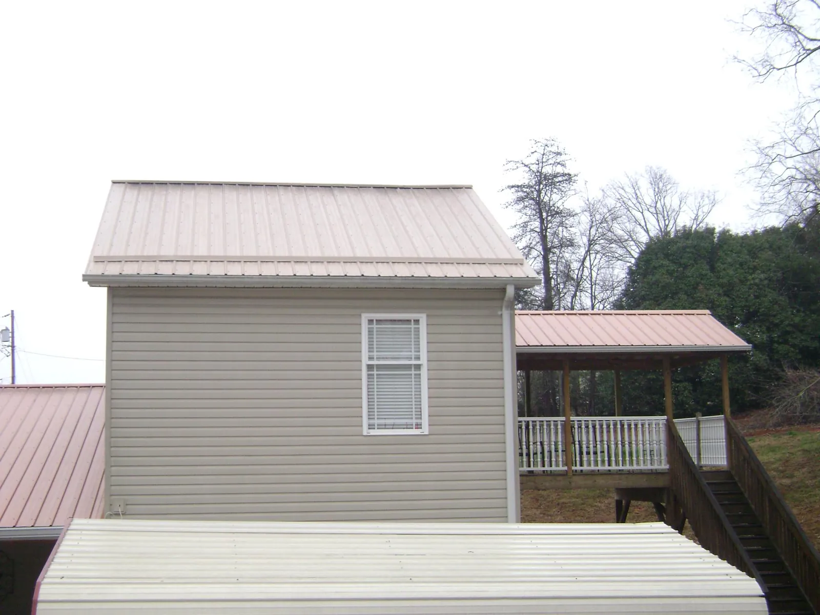 Tan metal roofs on a two story addition and attached porch, from a Roof Replacement job in Chester